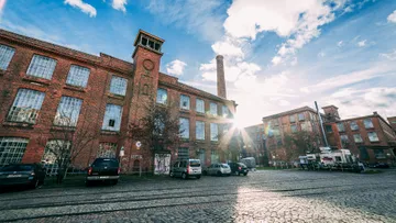 Brick building in sunlight, parked cars.