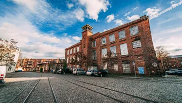 Brick building with clock in cobblestone street.
