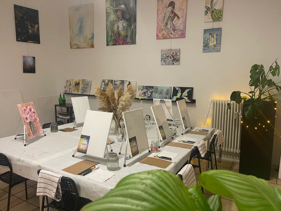 Art studio with easels, paintings, plant decor.