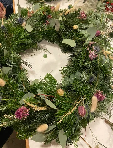 Wreath of pine branches with colorful dried flowers.