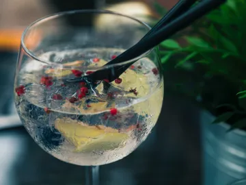 A glass of drink is stirred with a straw.