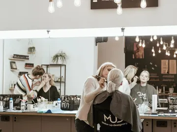 Ladies receive makeup in a cosmetic studio with mirrors.