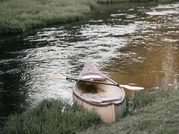 Canoe is situated on the banks of a calm body of water.