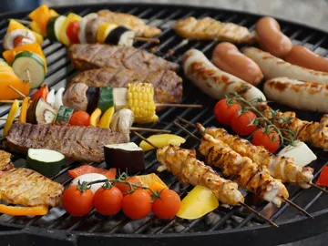 Gegrilltes Fleisch und Gemüse liegen auf einem Grill.
