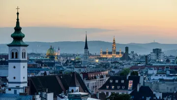 City skyline at sunset, church spires visible.