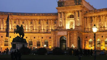 Historisches Gebäude bei Nacht beleuchtet mit Statue.
