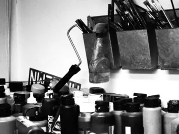 Paint cans and brushes are stored in a creative work area.