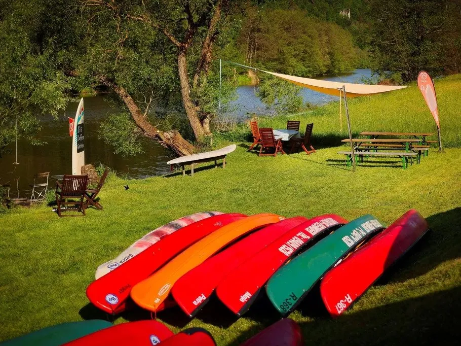 Colourful canoes lie in the grass on the riverbank.