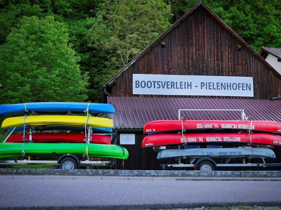 Bunte Kanus stehen vor einem Bootsverleih im Freien.