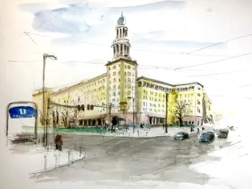 Large building with clock tower, people and vehicles in motion.