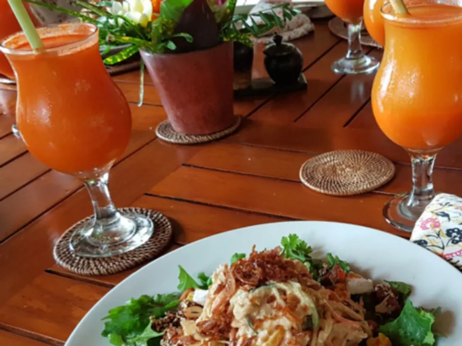 Ein Salatgericht liegt auf einem Tisch, umgeben von Getränken.
