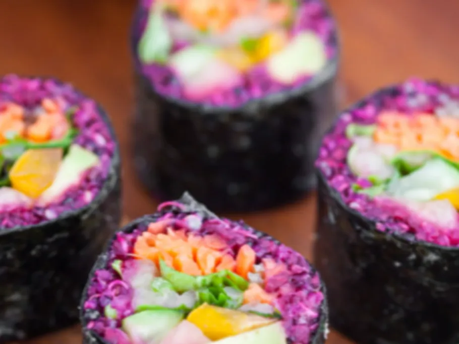 Bunte Sushi-Rollen liegen auf einem Holzbrett.