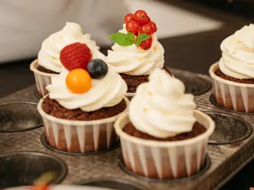 Cupcakes with cream and fruit in a baking dish.