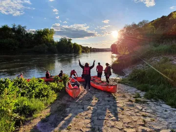 Kajaks stehen am Ufer, während Menschen feiern und entspannen.