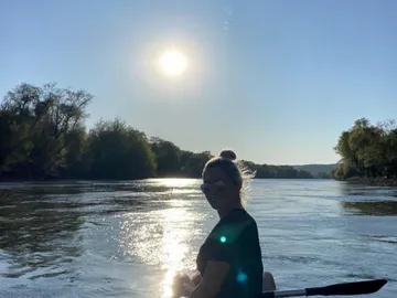 Frau paddelt auf ruhigem Wasser unter der Sonne.