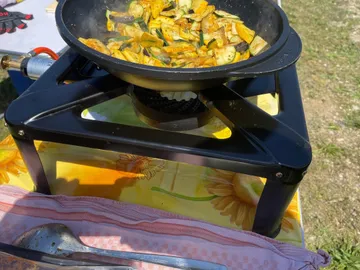 Pfanne mit Gemüse auf einem Gaskocher im Freien.