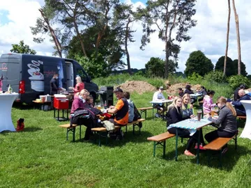 Eating and drinking outside, surrounded by trees.