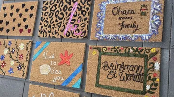 Colorful doormats displayed on gray tiles.