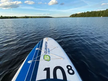 Stand-up paddleboard swims calmly on a still lake.