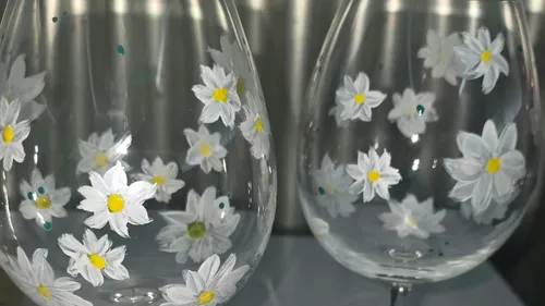 Gläser mit bemalten Blumen im Regal.