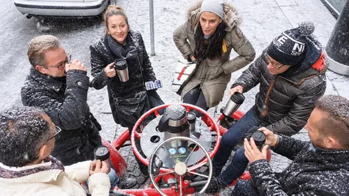 People drinking coffee outside in snowy weather.