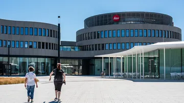 Two people walking towards modern circular building.