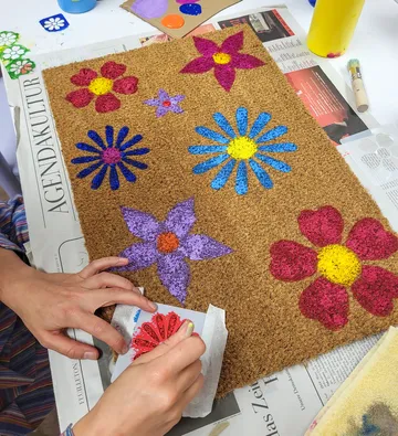 Hand painting colorful flowers on doormat.