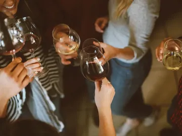 Glasses are lifted to toast a party together.