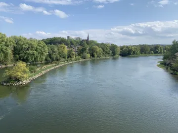 Ein Fluss fließt ruhig durch eine grüne Landschaft.
