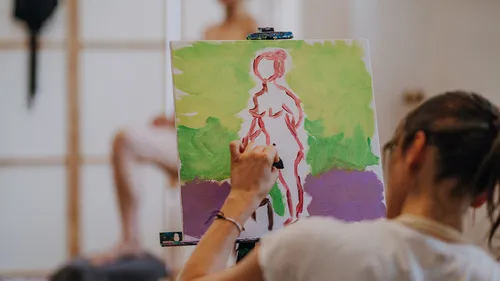 Artist painting a figure in a studio.