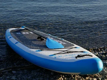 Stand-Up Paddleboard liegt am Ufer des Wassers.