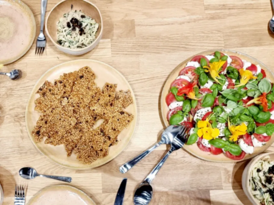 Verschiedene Gerichte auf Holzplatte, gemeinsam zum Essen angerichtet.