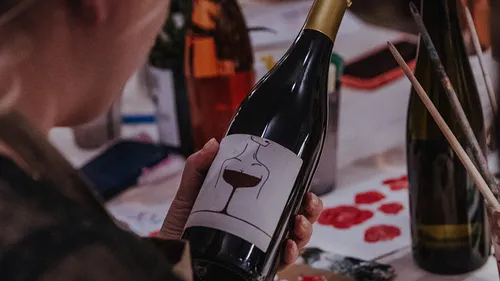 Person holding wine bottle at table.