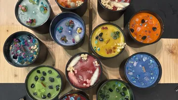 Colorful candles with gemstones on wooden surface.