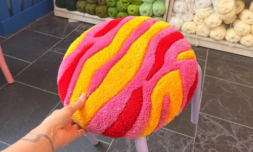 Colorful cushion on stool, hand holding it.