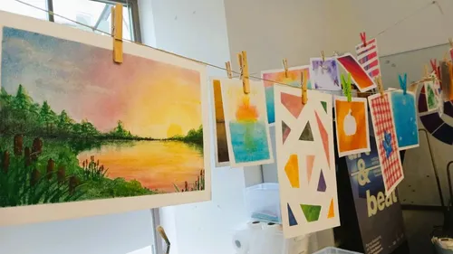 Art prints hanging on a line indoors.