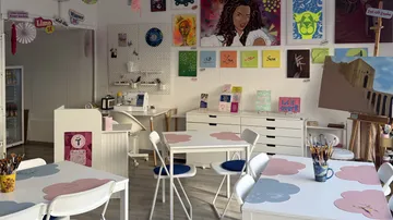 Art studio with colorful paintings and tables.