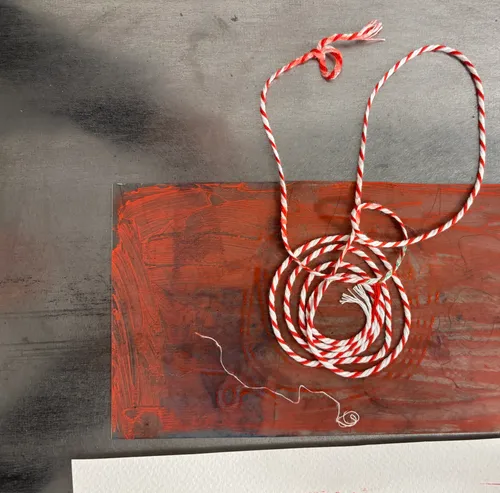 Red string coiled on red-painted surface.