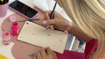 Person painting on white fabric indoors.