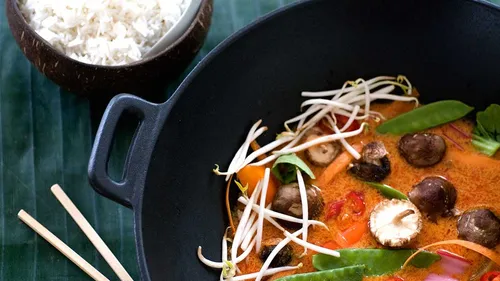 Thailändisches Curry mit Gemüse im schwarzen Topf.