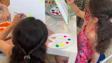 Children painting canvases at a table.