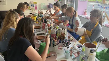 People painting pottery in art studio.