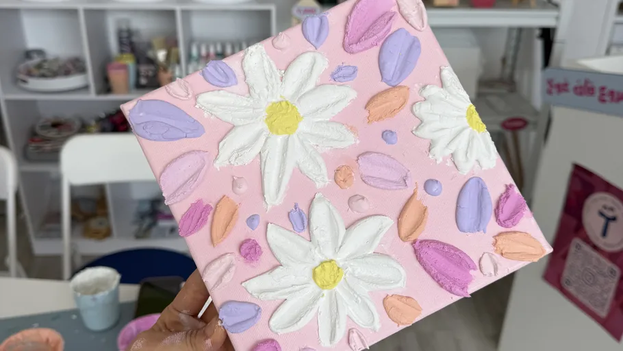 Hand holding daisy painting in studio.