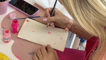 Person painting a canvas bag at a table.