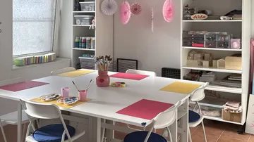 Craft room with table, chairs, and supplies.