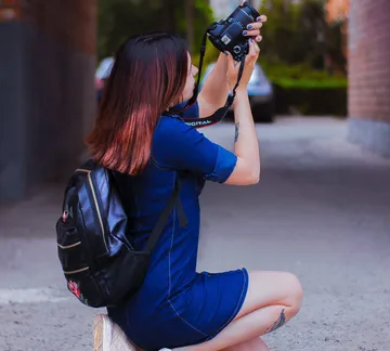 A person takes pictures with a camera in a street.