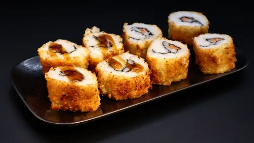 Sushi rolls on a black rectangular plate.