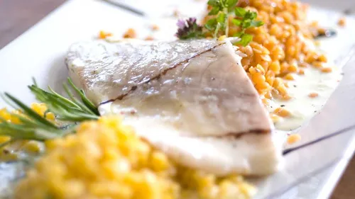 Fischfilet serviert mit Linsen und Kräutern.