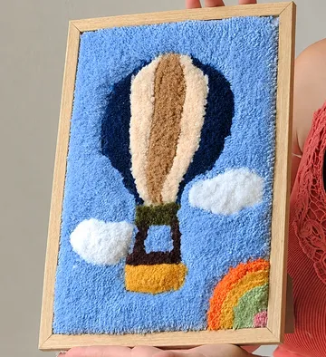 Hand holds framed textile hot air balloon.
