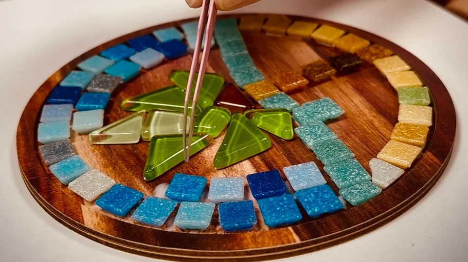 Mosaic artwork with pincers, wooden base.